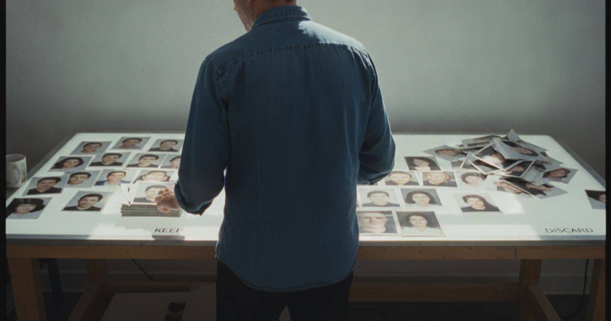 Una persona común en una mesa de luz seleccionando muchas fotos impresas, conservando algunas y descartando otras